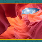 A view of Antelope Canyon showing eroded red sandstone formations and an opening in the top revealing the sky with clouds—perfect backdrops for fun celebration ideas and memorable birthday party tips.